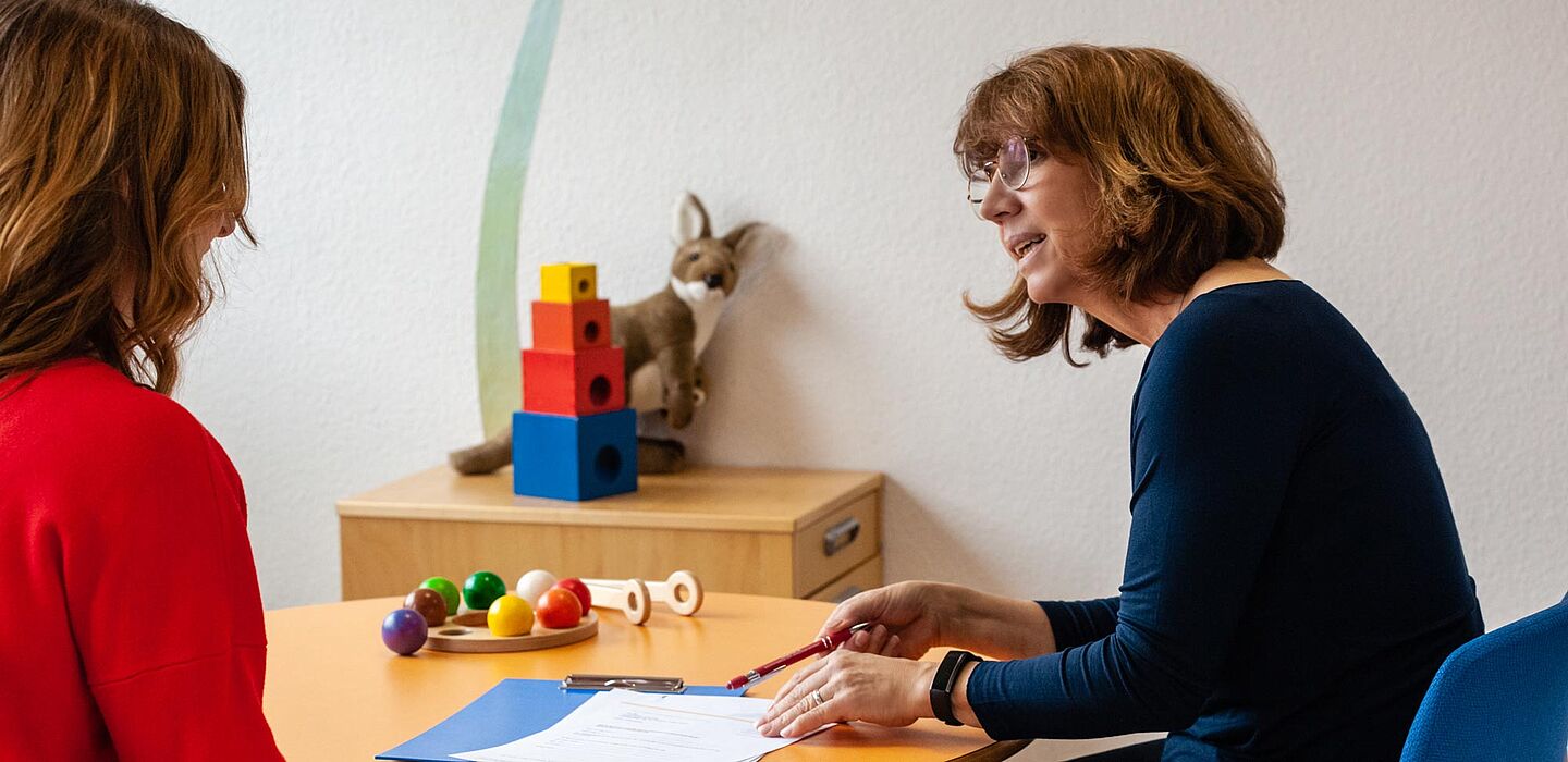 2 Frauen an einem Tisch im Gespräch. 